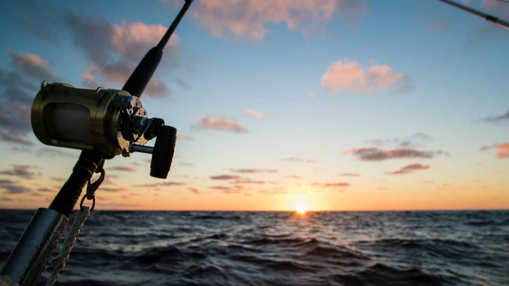 Baitcaster fishing rod with stunning sunset over the ocean